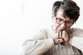 Catholic grandmother in melancholy praying to god with red rosary with cross Royalty Free Stock Photo