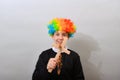 Catholic pastor in a clown wig with a cross and rosary. The concept of mockery of sectarianism and fanaticism