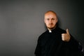 Catholic priest in black shirt with cleric collar showing OK