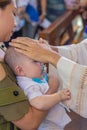 Catholic priest blessing a new born baby boy during a baptism. Royalty Free Stock Photo