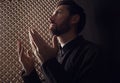 Catholic priest in cassock praying to God in confessional booth Royalty Free Stock Photo