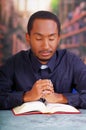 Catholic priest wearing traditional clerical collar shirt sitting with folded hands holding rosary while praying and Royalty Free Stock Photo