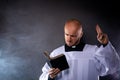 Catholic priest in white surplice and black shirt with cleric collar reading bible