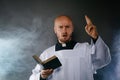 Catholic priest in white surplice and black shirt with cleric collar reading bible