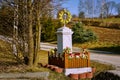 Catholic shrine with flowers and yellow decorations on the background of the field and road Royalty Free Stock Photo