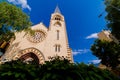 Catholic Cathedral Basilica with a high spire. Landscape against the blue sky. In the foreground are the crowns of trees Royalty Free Stock Photo