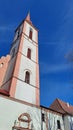 Catholics church bell tower with sculptures, blue clear sky