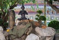 Cats have a rest near the sculpture of a meditating person in the territory of a Buddhist monastery