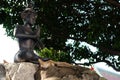 Cats have a rest near the sculpture of a meditating person in the territory of a Buddhist monastery