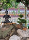 Cats have a rest near the sculpture of a meditating person in the territory of a Buddhist monastery