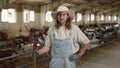 Cattleman in uniform using pitchfork for cleaning goat farm