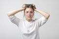 Cauasian woman in panic in studio. halding her head. She is holding her head with hands.