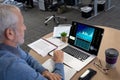 Caucacian senior businessman sitting at desk using laptop with statistical data on screen Royalty Free Stock Photo