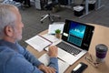 Caucacian senior businessman sitting at desk using laptop with statistical data on screen Royalty Free Stock Photo