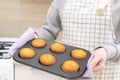 Caucasain woman holding tray with freshly made cupcakes or maffins at the kitchen