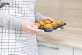 Caucasain woman holding tray with freshly made cupcakes or maffins at the kitchen