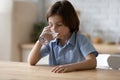 Caucasian 7s boy drinking fresh pure water in kitchen