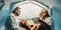 Caucasian adult couple smile and enjoy leisure inside a tent in free camping at the beach with sea view. Concept of alternative Royalty Free Stock Photo