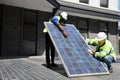 Caucasian and African American workers working on installing solar panel on the rooftop of the house for renewable energy and envi