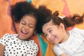 Happy cheerful ethnic girls  laying on mat at outdoors park, Her smiling and laughing together, Relationship little kids, Diverse Royalty Free Stock Photo