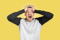 Caucasian angry man screaming out of control while holding his head in desperation. Isolated yellow background Royalty Free Stock Photo