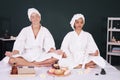 Caucasian and Asian woman in white bath towel for yoga meditation for create concentration and calm the mind on bed preparing for