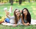 Caucasian and Asian young woman doing selfie and showing tongues