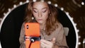 Caucasian woman makeup artist applies eyeshadow sitting in front of ring light