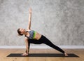 Caucasian attractive girl in yoga pose Bikram triangle standing against texturized wall Royalty Free Stock Photo