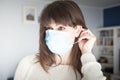 Caucasian attractive woman portrait putting on a blue face mask during covid-19 pandemic