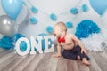 Caucasian baby boy in dark pants and blue bow tie celebrating his first birthday with letters one and balloons Royalty Free Stock Photo