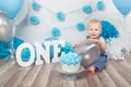 Caucasian baby boy in dark pants and blue bow tie celebrating his first birthday with letters one and balloons Royalty Free Stock Photo