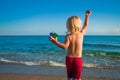 Caucasian baby boy throw stones to the sea