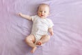 Caucasian baby girl boy with blue eyes four months old lying on bed looking at camera.