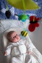 Baby playing with toys looking on mobil resting on bed