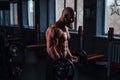 Caucasian bald topless man doing an exercise with a barbell in the gym. Bicep curls with weights.