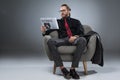 Caucasian bearded businessman in glasses sitting in armchair and reading newspaper,