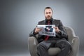 Caucasian bearded businessman sitting in armchair and with newspaper in hands while looking at camera, Royalty Free Stock Photo