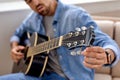 bearded man tuning acoustic guitar at home, Young guitarist fixing tuning pegs close-up Royalty Free Stock Photo