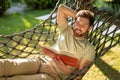 Caucasian bearded young man lying in hammock with a book in hands Royalty Free Stock Photo