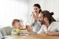 Caucasian beautiful parents take care of baby boy toddler in kitchen. Happy family, Attractive young couple cook and feed healthy