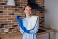 Caucasian beautiful red-headed female in casual clothes wearing rubber glove and holding chemica spray in kitchen