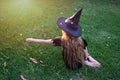 Causcasian blond girl with long hair in halloween witch costume sitting on a green grass Royalty Free Stock Photo