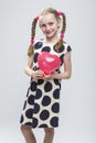 Caucasian Blond Girl With Pigtails Posing in Polka Dot Dress Against White.