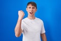 Caucasian blond man standing over blue background angry and mad raising fist frustrated and furious while shouting with anger Royalty Free Stock Photo