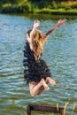 Caucasian Blond Woman in Dress Jumping Near Water Shore. Royalty Free Stock Photo