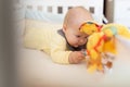 Caucasian blonde baby five months old lying on bed at home. Kid wearing cute clothing trendy colors: ultimate gray and Royalty Free Stock Photo