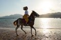 Caucasian blonde girl riding horse at sunset beach Royalty Free Stock Photo