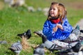 Caucasian blonde little girl feeding pigeons in a park on a sunny day. Royalty Free Stock Photo