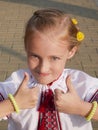 Caucasian blonde little girl in festive Ukrainian embroidered shirt gestures all the best Royalty Free Stock Photo